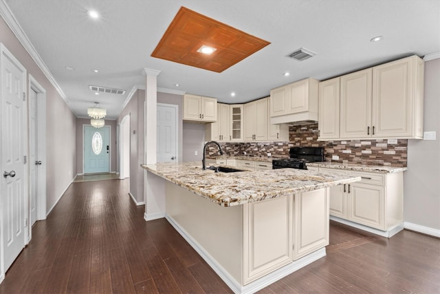 1910 Serenata Ln, Humble, TX 77396 - kitchen with black range with gas stovetop, a sink, cream cabinetry, tasteful backsplash, and light stone counters