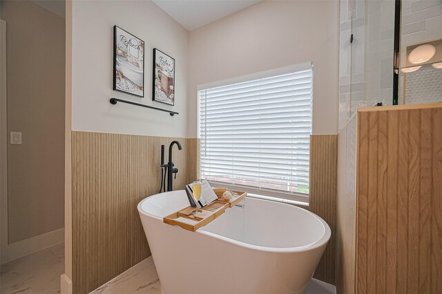 5615 Haven Point Dr, Houston, TX 77084 - full bathroom featuring marble look tiles, a wainscoted wall, a freestanding tub, and a shower