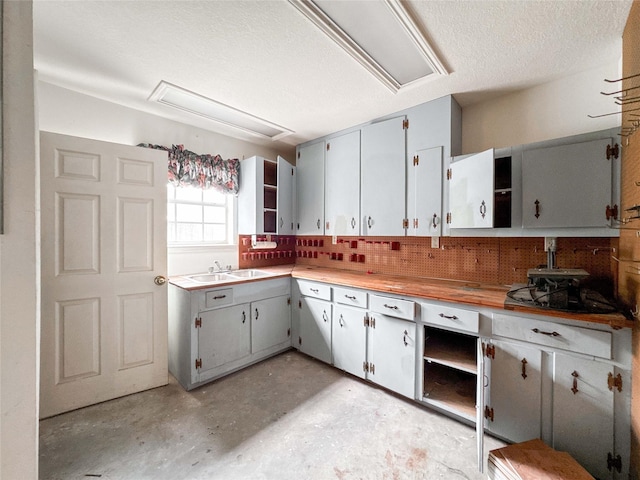 1507 N 24th St, Nederland, TX 77627 - kitchen featuring open shelves, a sink, tasteful backsplash, and concrete flooring