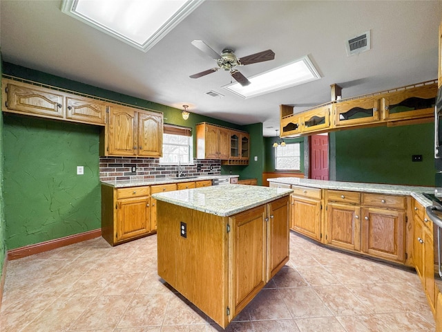 1507 N 24th St, Nederland, TX 77627 - kitchen featuring a center island, a sink, a skylight, glass insert cabinets, and ceiling fan