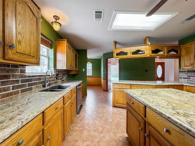 1507 N 24th St, Nederland, TX 77627 - kitchen with a sink, dishwasher, tasteful backsplash, brown cabinetry, and light stone counters
