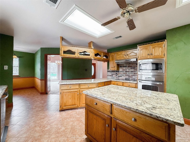 1507 N 24th St, Nederland, TX 77627 - kitchen featuring stainless steel appliances, baseboards, under cabinet range hood, a ceiling fan, and a peninsula