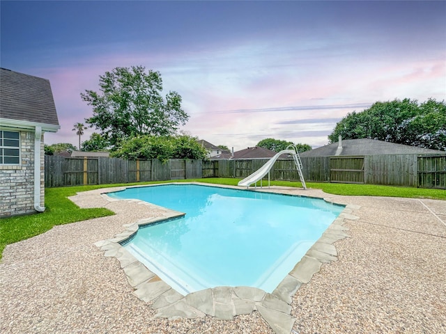 1507 N 24th St, Nederland, TX 77627 - pool at dusk with a water slide, a fenced backyard, and a patio area