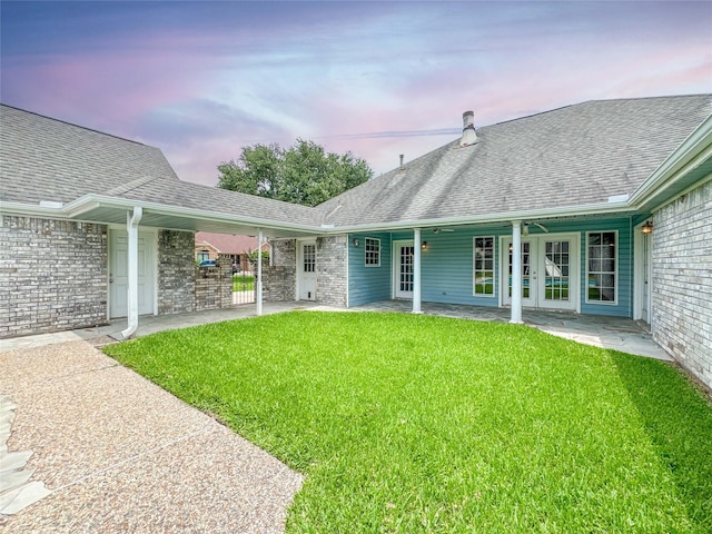 1507 N 24th St, Nederland, TX 77627 - back of property at dusk with a yard, a shingled roof, and french doors