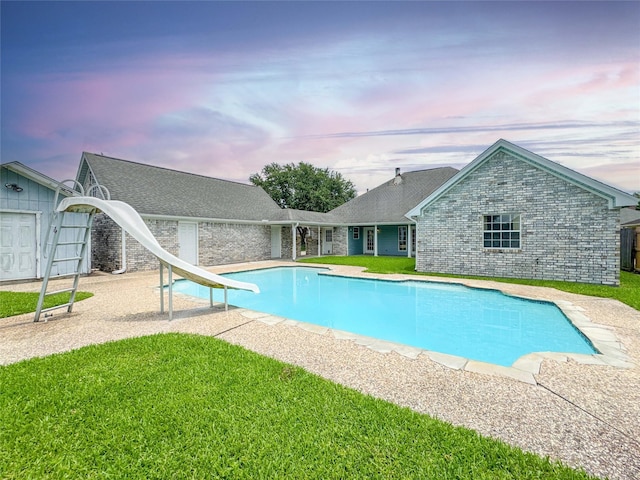 1507 N 24th St, Nederland, TX 77627 - pool at dusk with a water slide, an outdoor pool, a yard, and a patio area