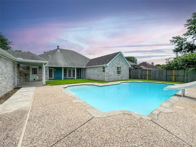 1507 N 24th St, Nederland, TX 77627 - pool at dusk featuring a water slide, french doors, and a patio area
