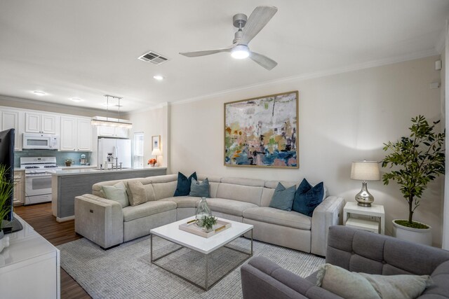 2703 Jackson St, Houston, TX 77004 - living room featuring dark wood-style flooring, ornamental molding, ceiling fan, and recessed lighting