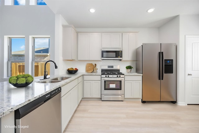 11749 Whirlaway Dr, Willis, TX 77318 - kitchen with appliances with stainless steel finishes, a sink, light stone countertops, light wood finished floors, and tasteful backsplash