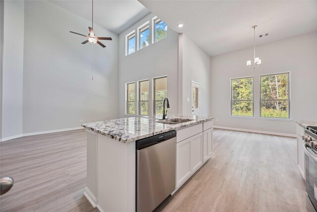 1497 Rd 66114, Dayton, TX 77535 - kitchen with dishwasher, a towering ceiling, light wood finished floors, a kitchen island with sink, and white cabinets