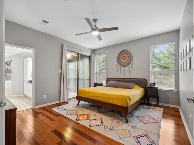 10 Leaf Trace Ct, The Woodlands, TX 77381 - bedroom featuring multiple windows, wood-type flooring, a ceiling fan, and connected bathroom