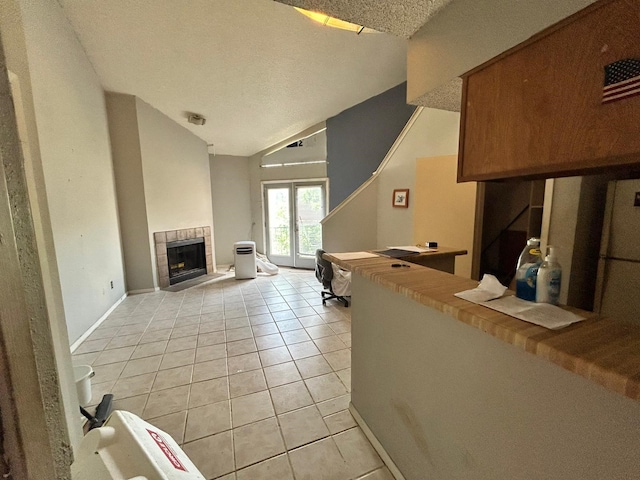 10855 Meadowglen Ln Unit 723, Houston, TX 77042 - living area with light tile patterned flooring, a tiled fireplace, lofted ceiling, a textured ceiling, and baseboards