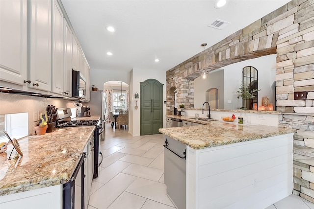 14222 Autumn Mist, Cypress, TX 77429 - kitchen featuring appliances with stainless steel finishes, arched walkways, a sink, light stone countertops, and light tile patterned floors