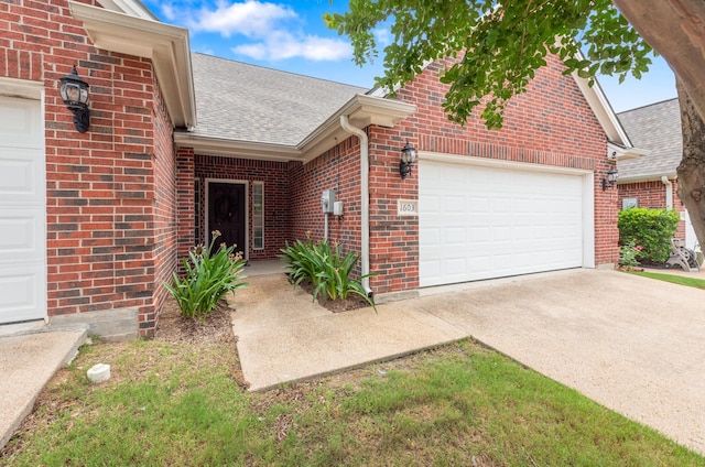 1603 Culture Ln, College Station, TX 77845 - doorway to property featuring an attached garage, a shingled roof, brick siding, and concrete driveway