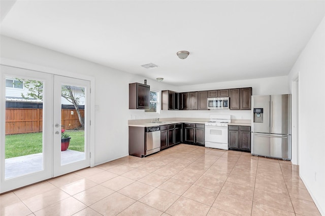 461 Mystic Glen Loop, Houston, TX 77339 - kitchen with stainless steel appliances, light countertops, french doors, dark brown cabinetry, and light tile patterned flooring
