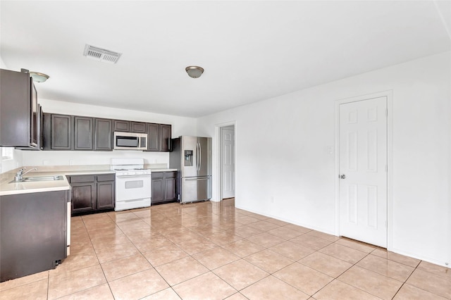 461 Mystic Glen Loop, Houston, TX 77339 - kitchen featuring stainless steel appliances, light countertops, light tile patterned floors, a sink, and baseboards