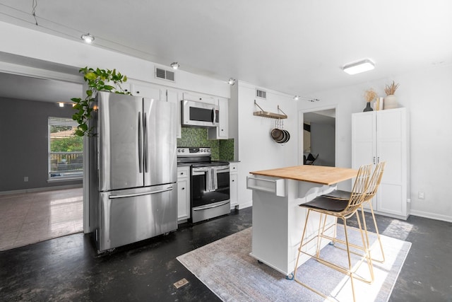 1919 Shadowdale Dr, Houston, TX 77043 - kitchen with stainless steel appliances, wood counters, tasteful backsplash, a kitchen bar, and white cabinets