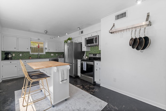 1919 Shadowdale Dr, Houston, TX 77043 - kitchen featuring appliances with stainless steel finishes, concrete floors, wood counters, decorative backsplash, and white cabinetry