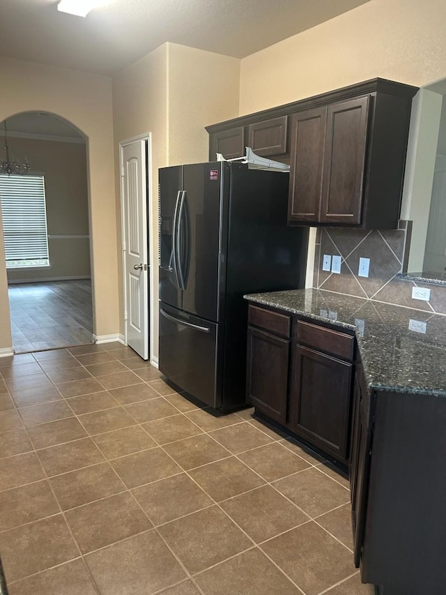 995 Arbor Gln, Conroe, TX 77303 - kitchen featuring refrigerator with ice dispenser, arched walkways, light tile patterned floors, dark stone countertops, and decorative backsplash