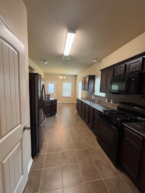 995 Arbor Gln, Conroe, TX 77303 - kitchen featuring black appliances, tile patterned flooring, a sink, a textured ceiling, and baseboards