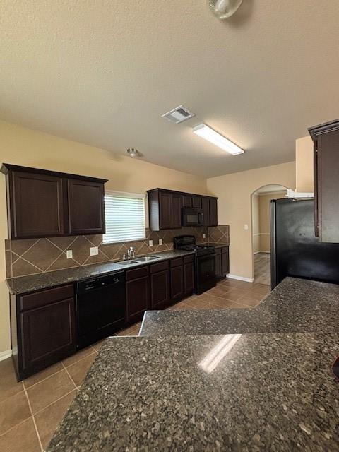 995 Arbor Gln, Conroe, TX 77303 - kitchen featuring black appliances, a sink, arched walkways, dark brown cabinets, and tile patterned floors