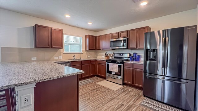 706 Hardwood Grove Ct, Houston, TX 77090 - kitchen featuring appliances with stainless steel finishes, a sink, a peninsula, light stone countertops, and recessed lighting