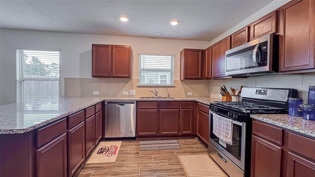 706 Hardwood Grove Ct, Houston, TX 77090 - kitchen with appliances with stainless steel finishes, a peninsula, plenty of natural light, light stone countertops, and recessed lighting