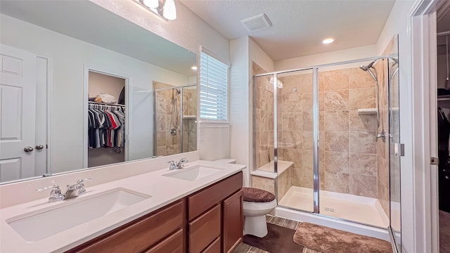 706 Hardwood Grove Ct, Houston, TX 77090 - bathroom with a walk in closet, a shower stall, toilet, double vanity, and a textured ceiling