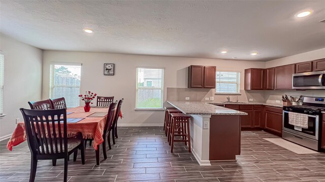 706 Hardwood Grove Ct, Houston, TX 77090 - kitchen with appliances with stainless steel finishes, a sink, wood tiled floors, a peninsula, and a breakfast bar