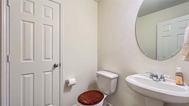 706 Hardwood Grove Ct, Houston, TX 77090 - half bath with a sink, toilet, baseboards, and a textured wall