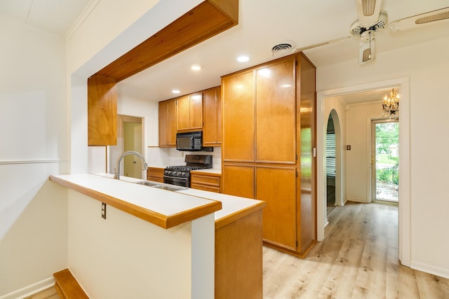 204 Caladium St, Lake Jackson, TX 77566 - kitchen featuring range with gas cooktop, black microwave, backsplash, light wood-style floors, and crown molding