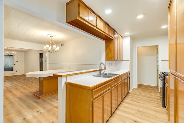 204 Caladium St, Lake Jackson, TX 77566 - kitchen with a sink, a chandelier, a peninsula, light wood-style flooring, and light countertops