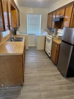 3431 Lantern Ln Unit 4, Baytown, TX 77521 - kitchen with freestanding refrigerator, electric range, brown cabinetry, light countertops, and a sink