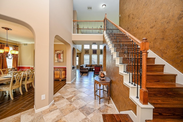 4214 Bridgestone Shadow Ct, Spring, TX 77388 - stairway featuring arched walkways, baseboards, a chandelier, a towering ceiling, and stone finish floors