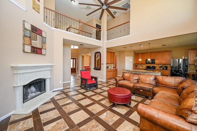 4214 Bridgestone Shadow Ct, Spring, TX 77388 - living room featuring ceiling fan, baseboards, inlaid floor details, a fireplace with raised hearth, and arched walkways