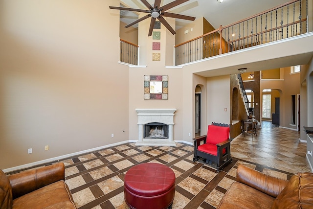 4214 Bridgestone Shadow Ct, Spring, TX 77388 - living area featuring baseboards, arched walkways, ceiling fan, a towering ceiling, and a premium fireplace