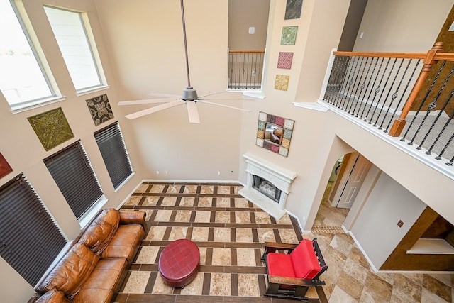 4214 Bridgestone Shadow Ct, Spring, TX 77388 - unfurnished living room featuring a fireplace with raised hearth, a towering ceiling, ceiling fan, stairs, and baseboards
