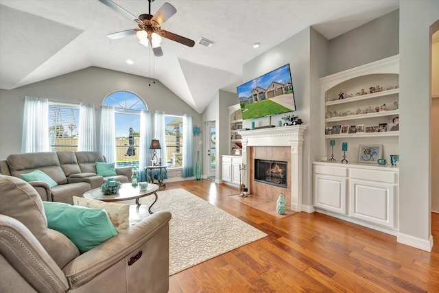 2206 E Van Trease Dr, Deer Park, TX 77536 - living room featuring a ceiling fan, wood finished floors, a tiled fireplace, lofted ceiling, and built in shelves