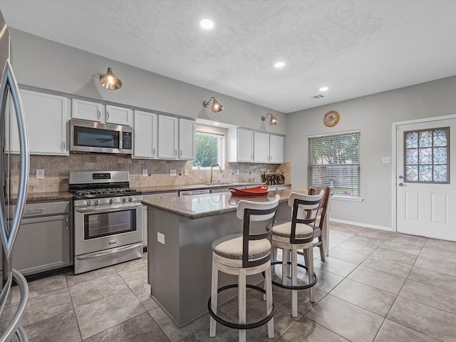2710 Magnolia Walk, Spring, TX 77388 - kitchen with stainless steel appliances, tasteful backsplash, stone countertops, a textured ceiling, and a breakfast bar area