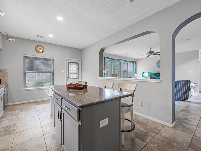 2710 Magnolia Walk, Spring, TX 77388 - kitchen with arched walkways, a kitchen bar, a center island, dark stone countertops, and ceiling fan