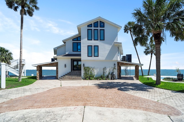102 Lanai St, Tiki Island, TX 77554 - view of front facade with curved driveway, a water view, french doors, and stairs