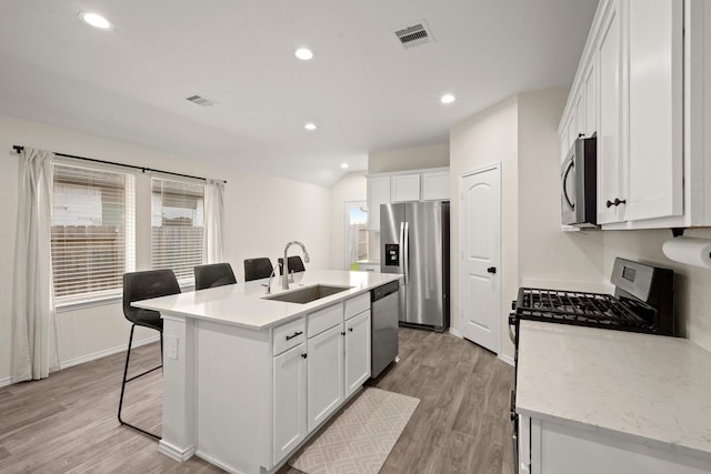 20010 Sienna Green Dr, Hockley, TX 77447 - kitchen featuring appliances with stainless steel finishes, a sink, a center island with sink, a breakfast bar, and white cabinetry