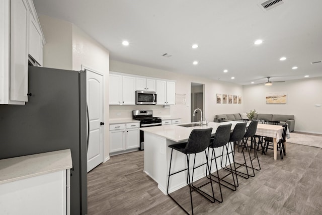 20010 Sienna Green Dr, Hockley, TX 77447 - kitchen with stainless steel appliances, a sink, recessed lighting, light wood-type flooring, and a kitchen breakfast bar