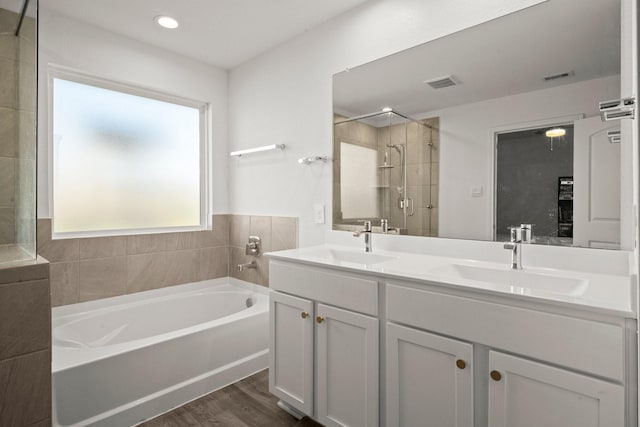 20010 Sienna Green Dr, Hockley, TX 77447 - full bathroom featuring a garden tub, double vanity, wood finished floors, and a stall shower