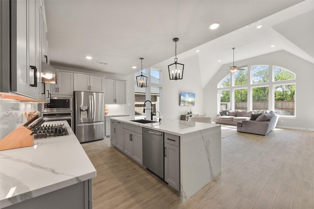5107 Shimmering Brook Ln, Fulshear, TX 77441 - kitchen with stainless steel appliances, a sink, gray cabinetry, a ceiling fan, and light wood-style floors