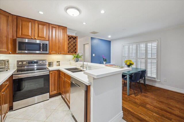 2513 Bering Dr Unit 13, Houston, TX 77057 - kitchen with stainless steel appliances, a sink, ornamental molding, a peninsula, and decorative backsplash