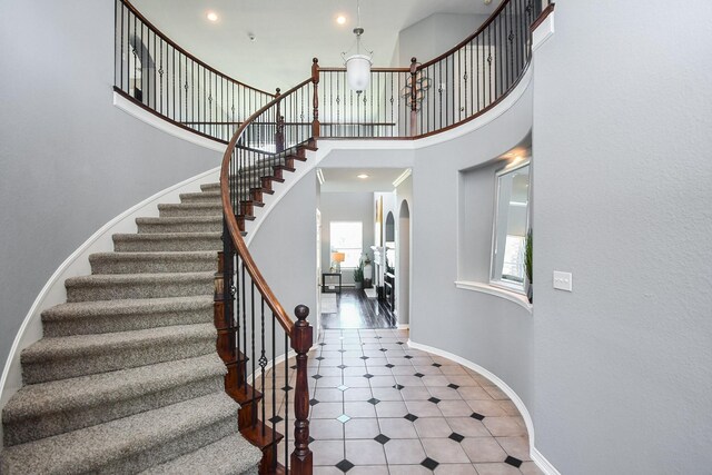 31 Hope Farm Rd, Missouri City, TX 77459 - stairway featuring a towering ceiling, baseboards, tile patterned floors, recessed lighting, and arched walkways