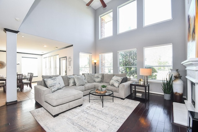 31 Hope Farm Rd, Missouri City, TX 77459 - living room featuring dark wood-type flooring, ceiling fan, a high ceiling, a fireplace with raised hearth, and baseboards
