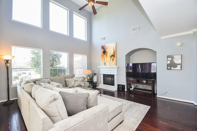 31 Hope Farm Rd, Missouri City, TX 77459 - living room featuring ceiling fan, a towering ceiling, dark wood finished floors, baseboards, and a glass covered fireplace