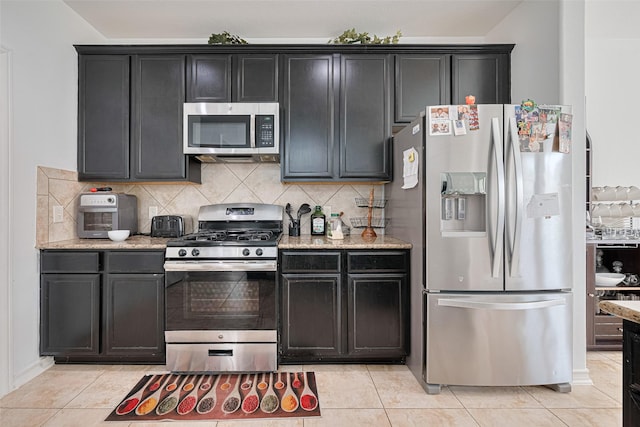 2019 Argos Dr, Missouri City, TX 77459 - kitchen with appliances with stainless steel finishes, decorative backsplash, light stone countertops, and light tile patterned floors