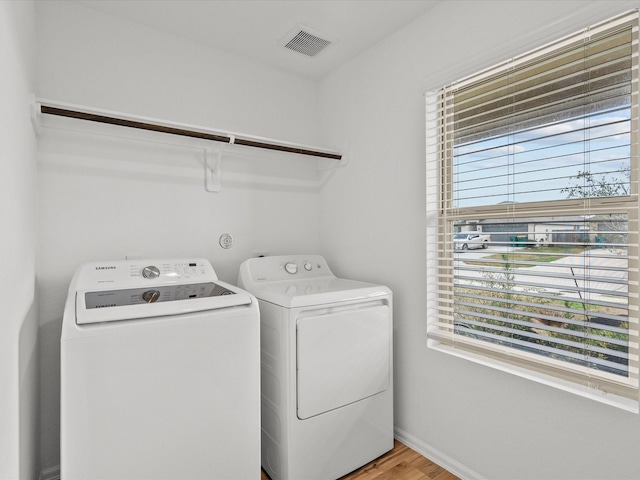 512 Maple Bnd, La Marque, TX 77568 - laundry room featuring healthy amount of natural light, washer and clothes dryer, light wood-style flooring, and baseboards